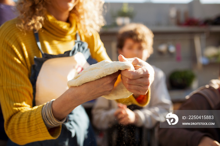 Midsection of woman kneading dough while teaching boys in yard