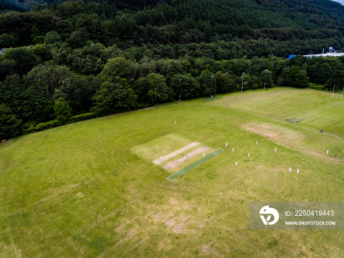 Aerial view of players, playing a game of Cricket on a Welsh Park Pitch in the summer