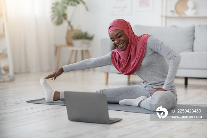 戴头巾的黑人穆斯林妇女在家里的笔记本电脑前锻炼