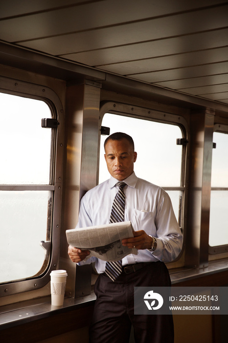 Man reading newspaper and having coffee on ferry