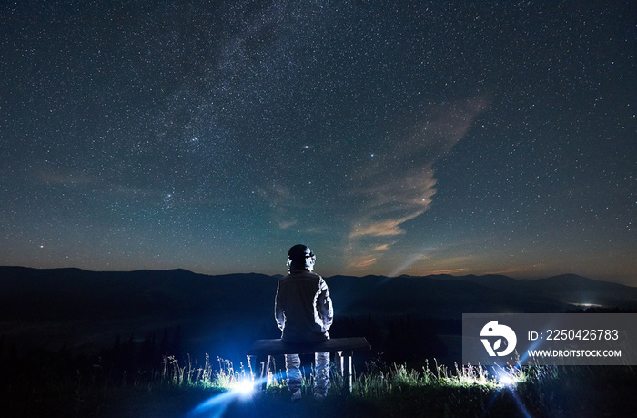 宇航员坐在长椅上眺望壮丽的星空。穿着太空服的宇航员尽情享受