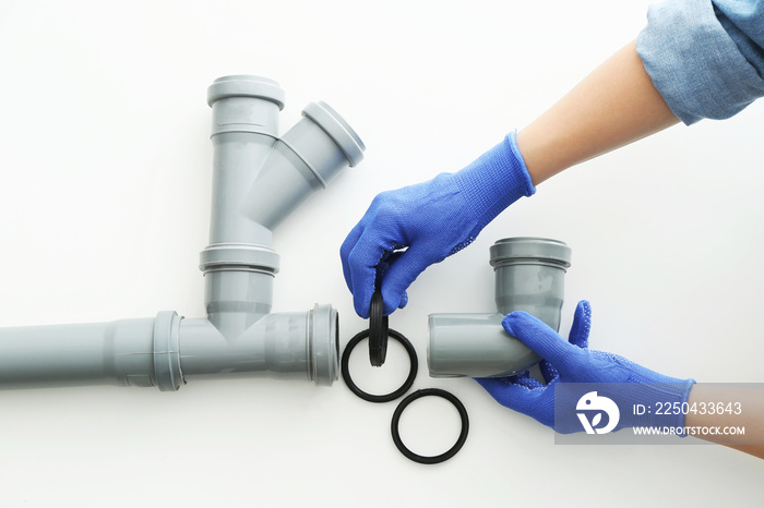 Plumber working with drain pipe on white background