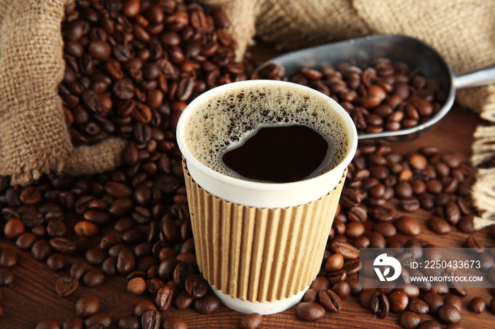 Cup of coffee with beans and scoop on table