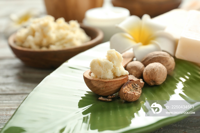 Bowl with shea butter, nuts and flower on plate