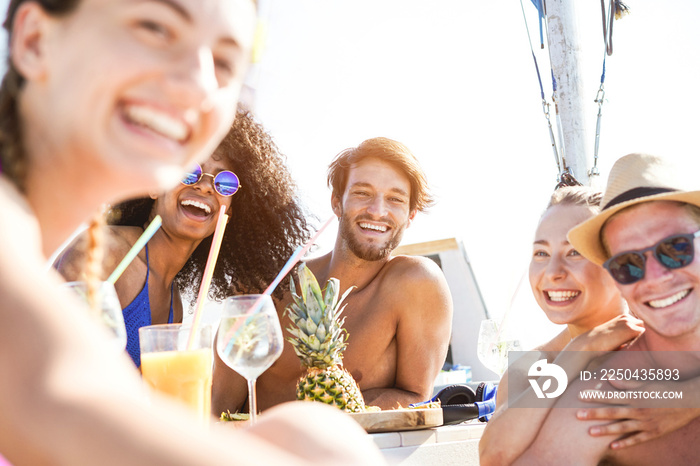 Happy multiracial friends drinking tropical cocktails at boat party - Young people having fun in sea