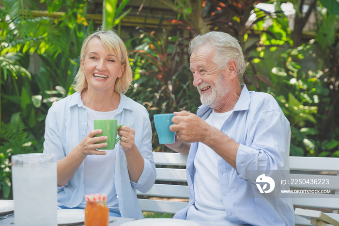 Happy senior couple relaxing drinking coffee in the morning at home garden