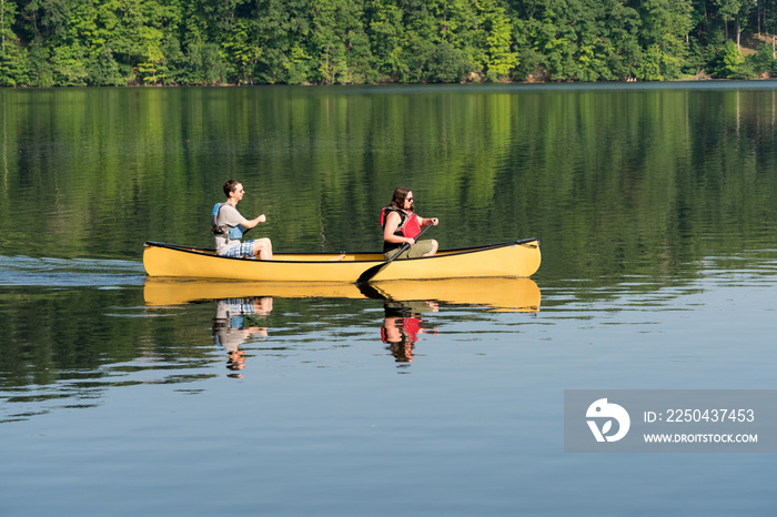 Couple paddling in yellow canoe on tree lined lake