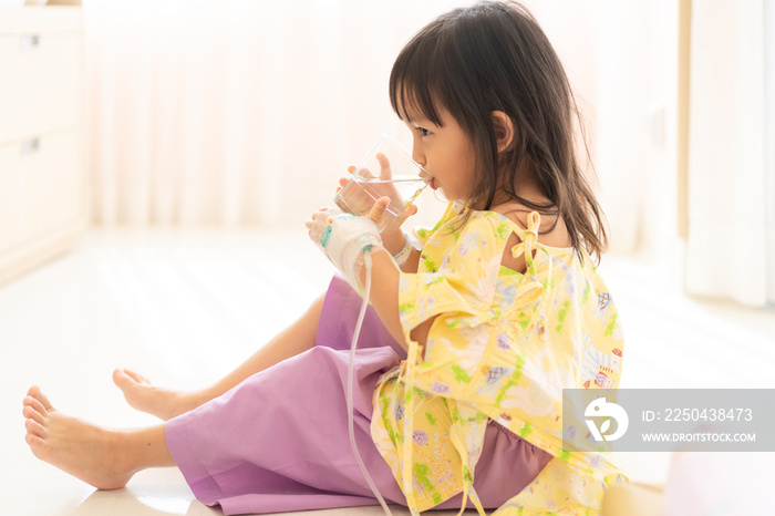A cute 3 years old girl is drinking the water in the hospital room when she admit as in patient with