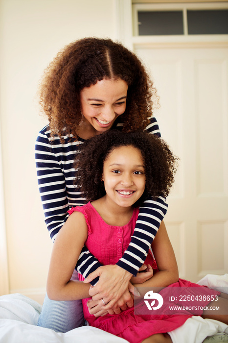 Mother embracing daughter (8-9) in bedroom