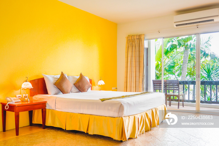 带阳台的浪漫素黄色卧室的内部装饰。它由床和白色枕头组成