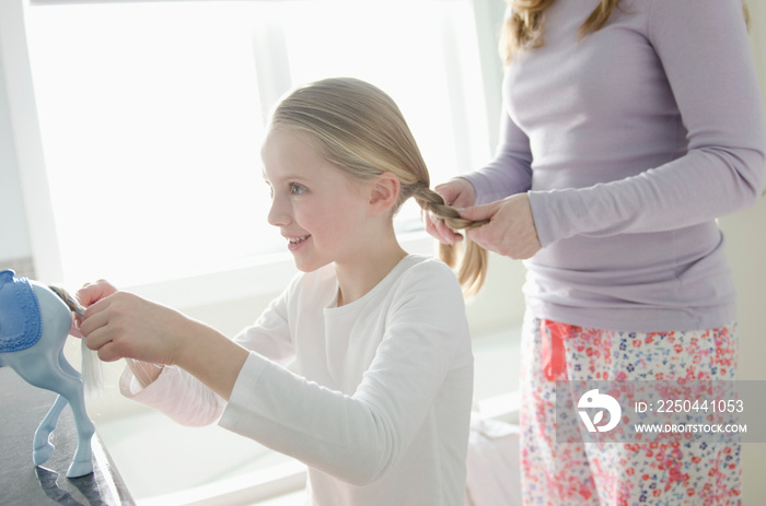 mother braiding daughters hair