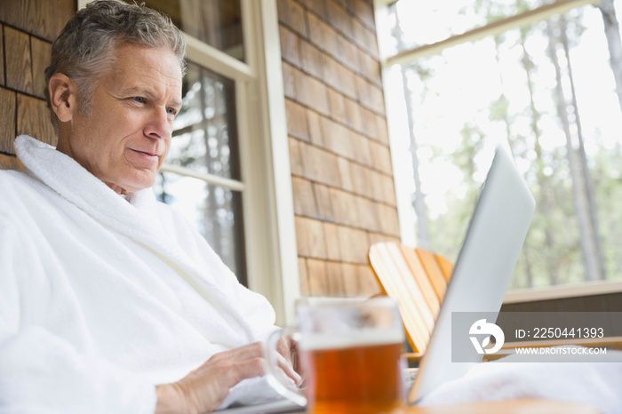 Middle-aged man relaxing on porch with laptop