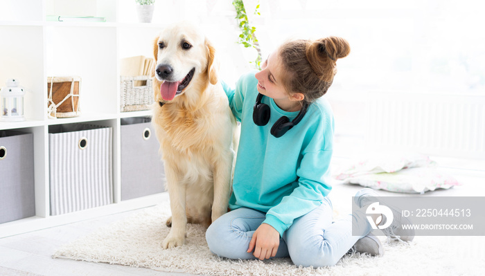 快乐的女孩和可爱的金毛猎犬在明亮的房间里