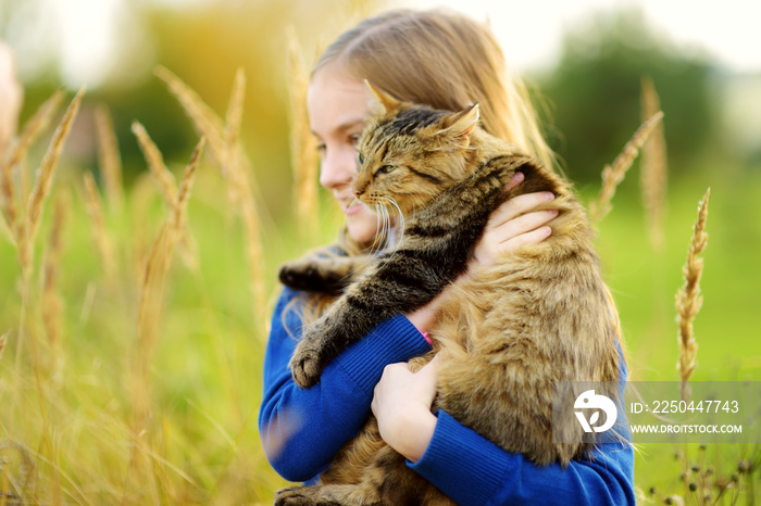阳光明媚的秋天，可爱的小女孩和她的猫在一起。可爱的孩子抱着他的宠物小猫。