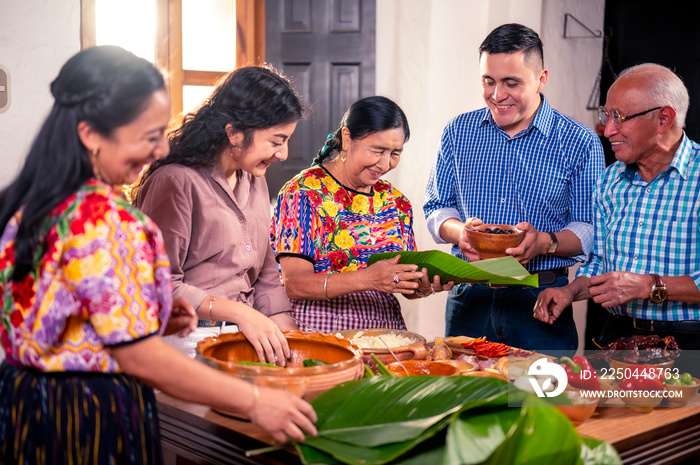 Una feliz familia latina se divierte cocinando una tradición guatemalteca con sus nietos.