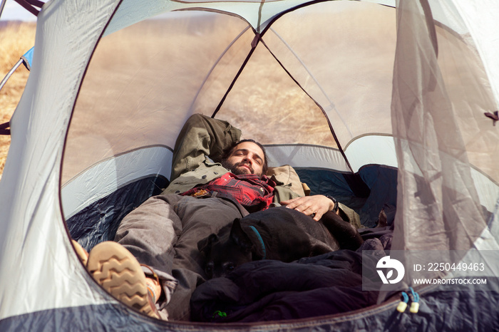 露营地男人和狗睡在帐篷里的全长