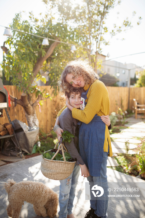 Smiling mother embracing son while standing on footpath in yard