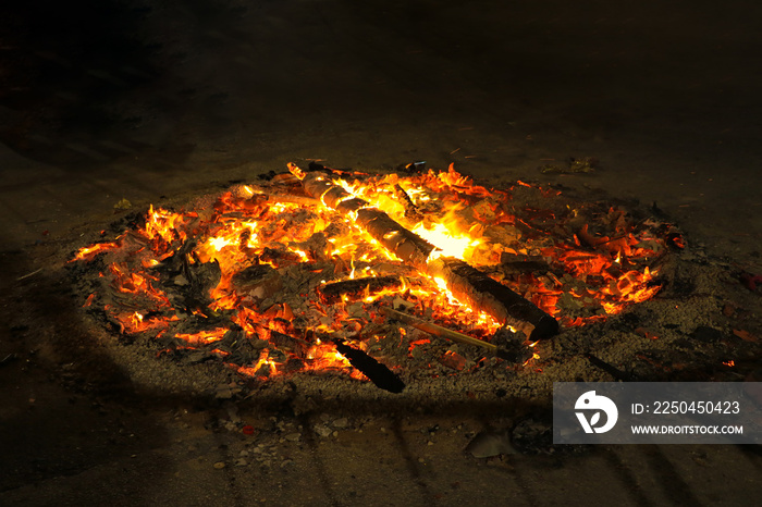 A fire pit on a street after a celebration. The wood is still glowing and it is very hot.