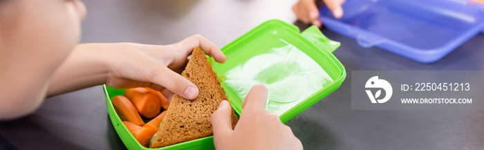 cropped view of schoolgirl taking toast from lunch box with fresh carrots, horizontal concept