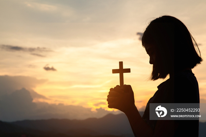 Religious concepts. Silhouette of a girl holding a crucifix to God. Morning with beautiful sunrise, 