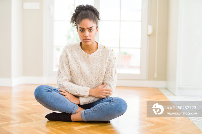 Beautiful young african american woman with afro hair sitting on the floor skeptic and nervous, disa