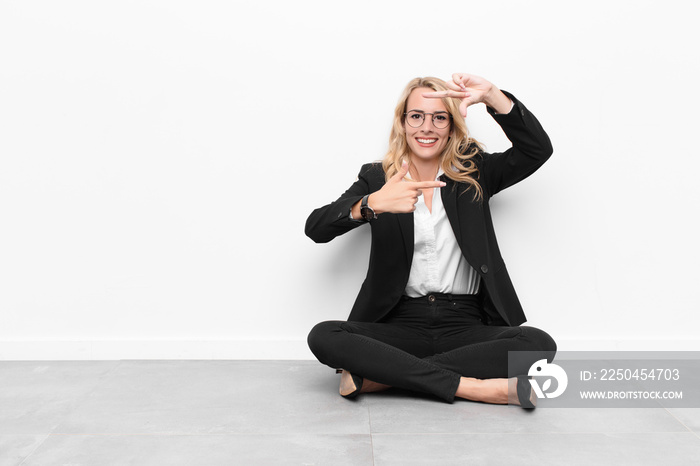 young blonde woman feeling happy, friendly and positive, smiling and making a portrait or photo fram