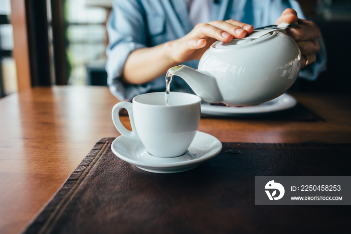 Females hands pour tea from teapot