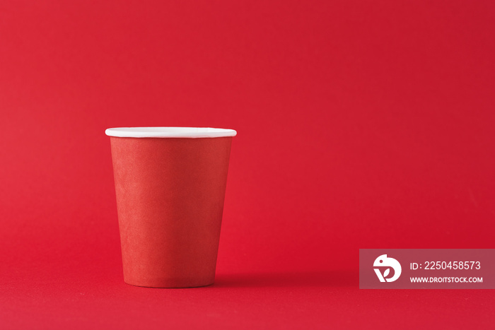 Red paper coffee cup on red background with a copy space. Minimalism style