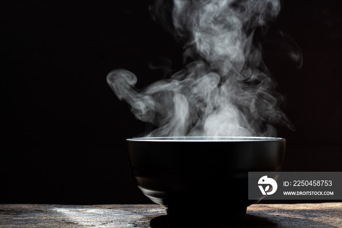 Bowl of hot soup. steam of hot soup with smoke wood bowl on dark background.selective focus,hot food