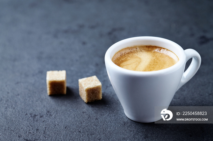 一杯咖啡和两块深色石头背景的红糖。特写。