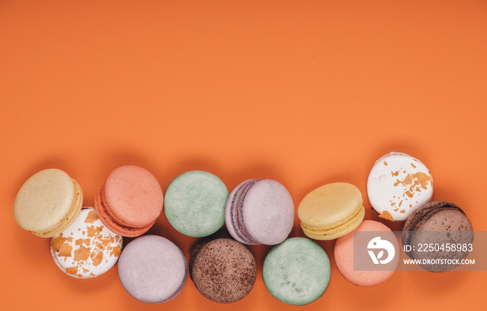 Sweet delicious colorful set of macaron on coral or orange background. French traditional dessert