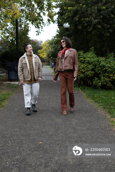 lifestyle image of transgender nonbinary friends talking and walking in the park