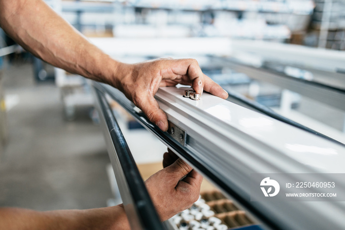 Manual worker assembling PVC doors and windows. Manufacturing jobs. Selective focus. Factory for alu