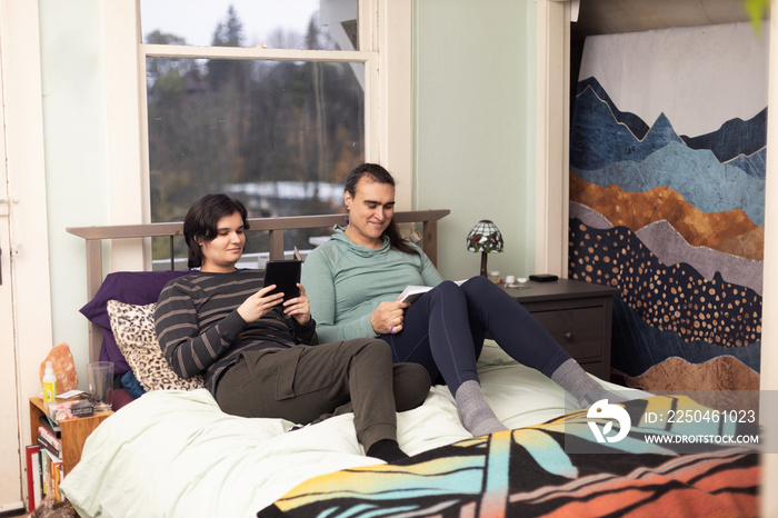 Trans friends reading on the bed.