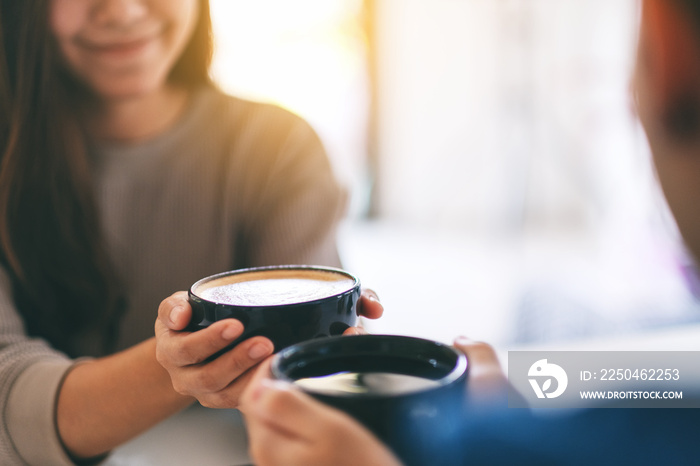 Closeup image of a man and a woman holding two coffee cups together