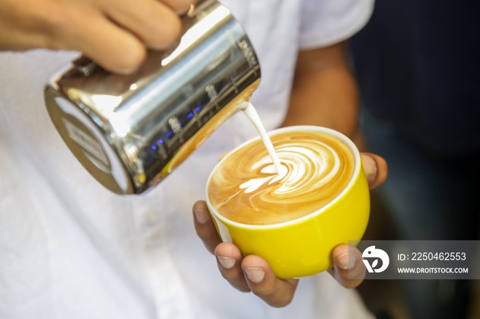 Close up image of barista hands pouring milk and preparing fresh cappuccino coffee