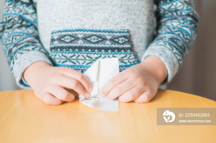 Kid folding a paper plane (origami).