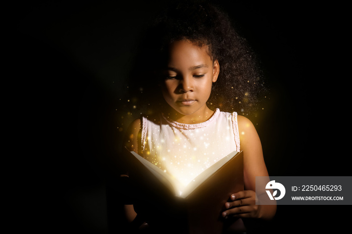 在黑暗背景下读书的非洲裔美国小女孩