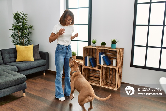 Young caucasian woman feeding dog standing at home