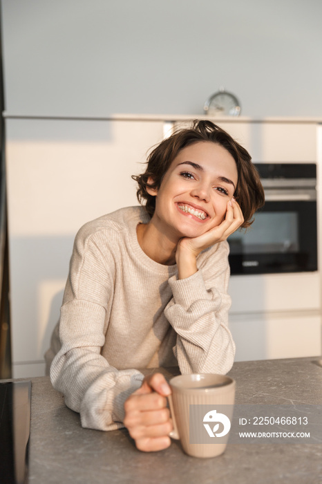 Vertical image of Smiling brunette woman drinking coffee