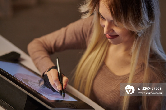 girl artist draws a digital pen on a professional tablet in her studio