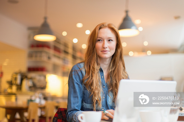 Young woman working at laptop in cafe