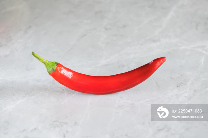 One hot chili pepper on grey marble background, crescent shaped. use for arabic sauce harissa, georg