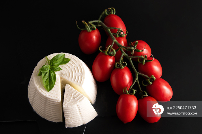 Front view view of fresh ricotta cheese with basil and cherry tomatoes on black plate italian food c