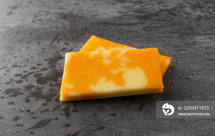 Two Colby Jack cheese bars on a gray background side view.