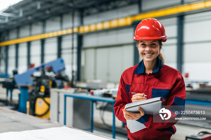 Portrait of a smiling engineer in protective work wear in industrial building.