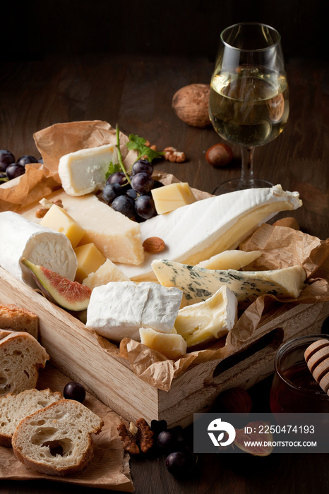 Variety of different cheese with wine, fruits and nuts. Camembert, goat cheese, roquefort, gorgonzol