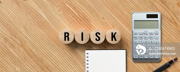 message RISK with calculator, pen and notepad on wooden background