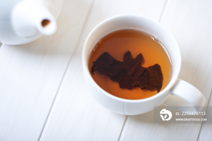 Halloween bat make from tea leaves into tea cup on white wooden table. Halloween celebration concept