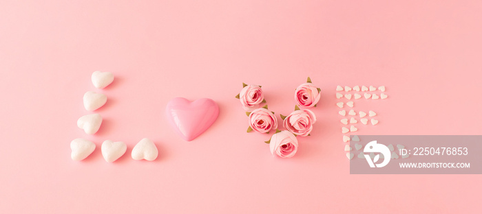 Word Love made of hearts shape candies and roses on pink background. Valentines day concept. Love co